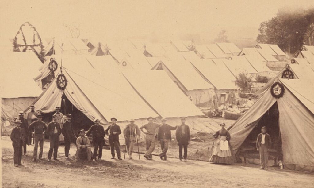 Group of wounded soldiers with two female nurses in front of tents at General Hospital, near Gettysburg, Pennsylvania